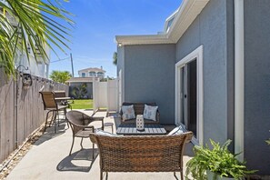 An outdoor patio with wicker furniture, a table, and a potted plant.