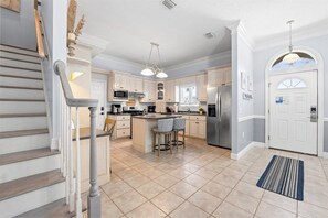 A kitchen with a central island, stainless steel appliances, and a staircase leading to another level. - Hot Tub, Sleeps 10, 1 block to beach access, Pets (Panama City Beach)