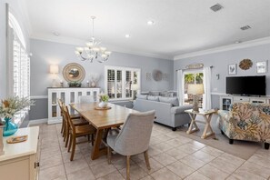 A spacious living area with a dining table, sofas, and a television.