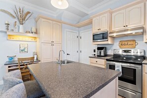 A kitchen with granite countertops, stainless steel appliances, and light-colored cabinetry. - Hot Tub, Sleeps 10, 1 block to beach access, Pets (Panama City Beach)