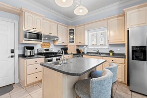 A modern kitchen with a central island, stainless steel appliances, and light-colored cabinetry.