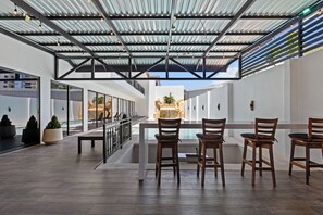 Terraza en la azotea con piscina, sillas de madera y vistas a la ciudad.
