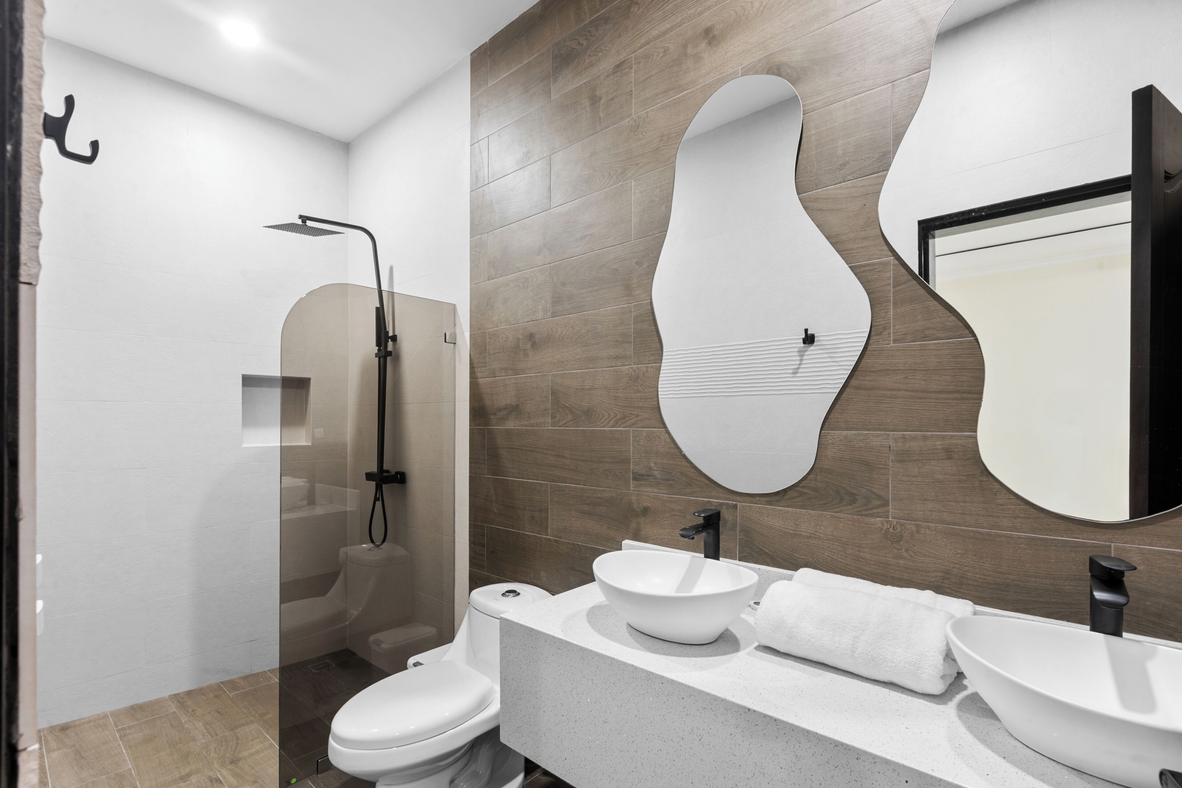 Une salle de bain moderne équipée d’une douche, de toilettes et d’un meuble-lavabo avec un évier et un miroir.