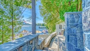 A stone staircase leading to a terrace with a view of a body of water and boats. - Luxury Meets the Lake (Lake George)