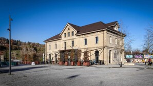 En stor, historisk bygning med en symmetrisk facade, store vinduer og en central indgang.