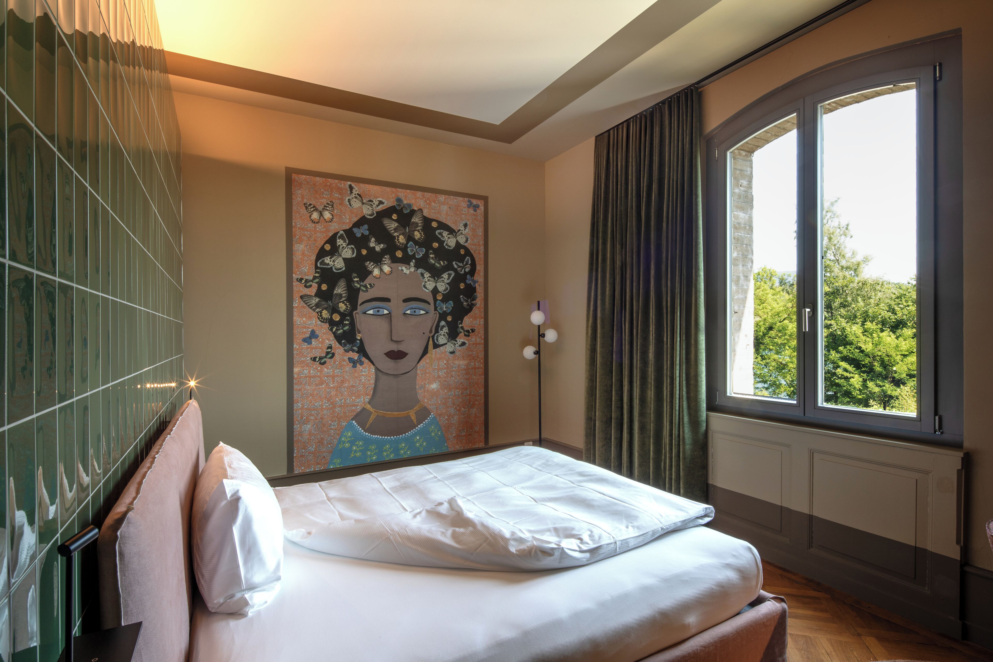 Una camera da letto con un letto, un quadro al muro, una finestra con tende e un termosifone.