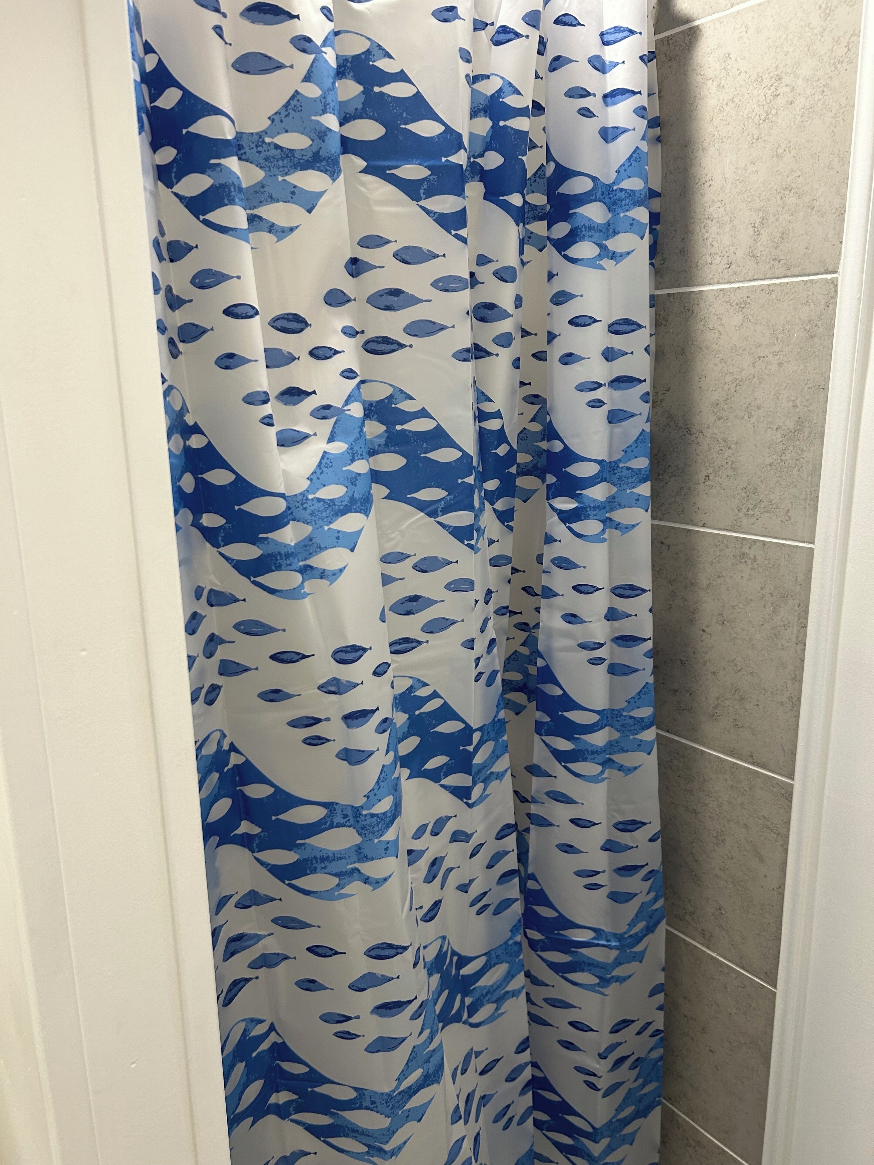 A bathroom with a shower curtain featuring a blue and white leaf pattern.