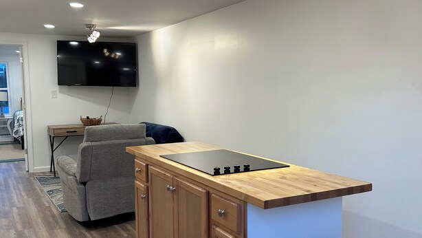 A modern kitchen with wooden cabinets, a black countertop, and a built-in stove.