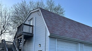 A blue Elantra parked in front of a white building with a garage and a wooden staircase.