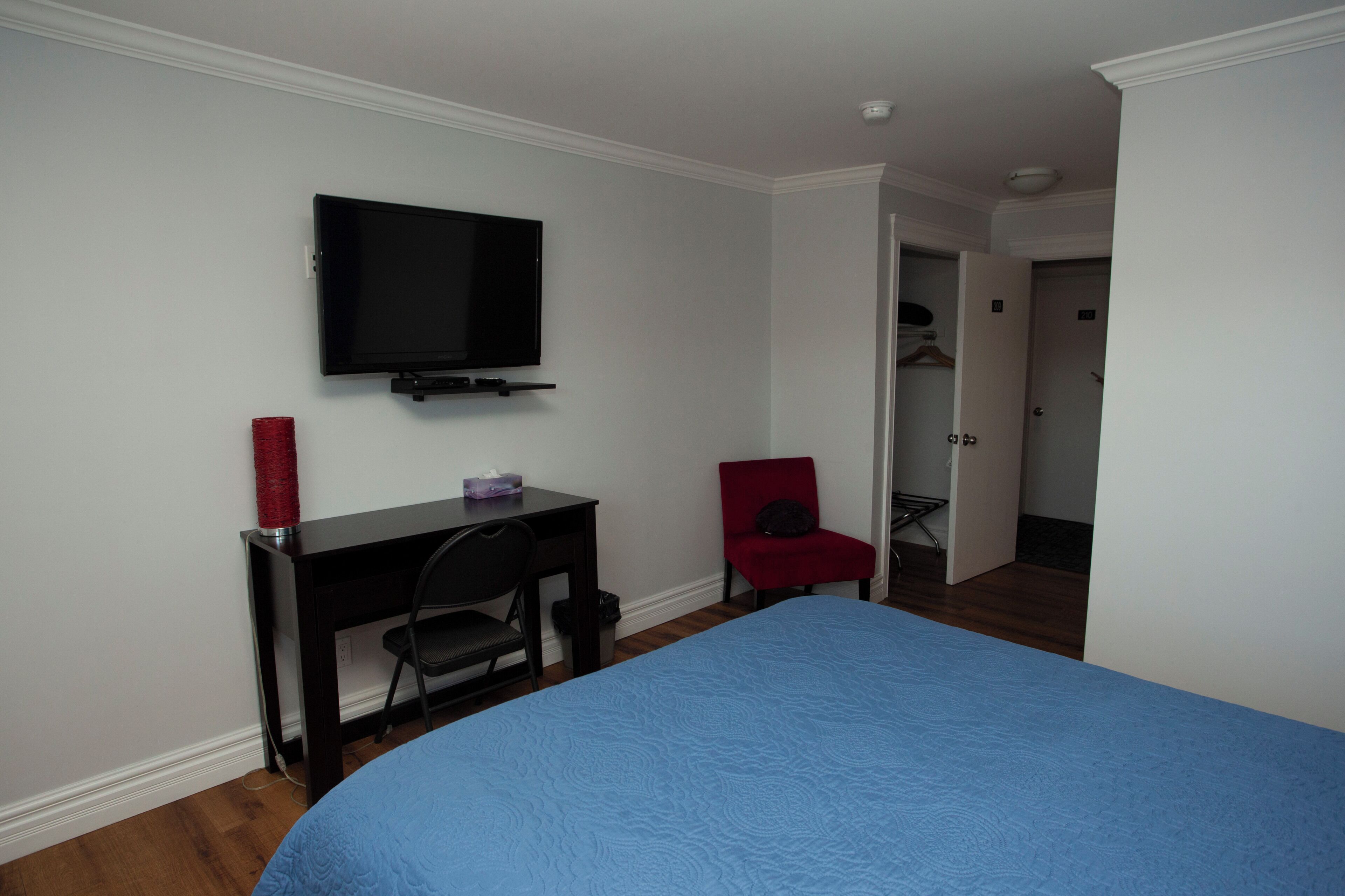 Une chambre à coucher comprenant un lit, un bureau, une chaise, un téléviseur et un placard.
