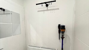 A small, white-walled room with a radiator, a black ceiling-mounted rack, and a blue cleaning tool. - Small and fine city apartment in Saarbrücken (Saarbrücken)