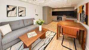 En moderne stue med sofa, sofabord og et spiseområde med bord og stole.