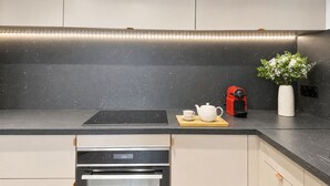 Et moderne køkken med en sort bordplade, indbygget ovn og kaffemaskine på disken.