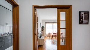 Une cuisine moderne avec des meubles gris et un évier en acier inoxydable, qui donne sur un coin repas avec une table et des chaises en bois.