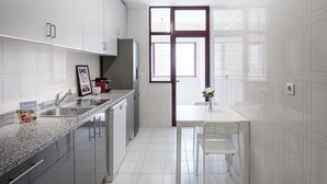 Une cuisine moderne avec des meubles blancs, un plan de travail en granit et un réfrigérateur en acier inoxydable.