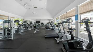 A modern gym with various exercise equipment, large windows, and a clean, spacious layout.