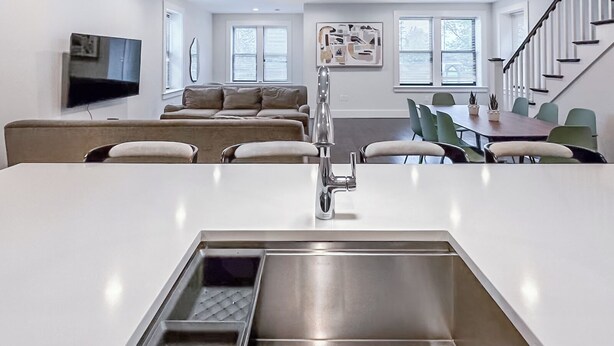 Una cocina moderna con una isla central, un comedor con mesa y sillas, un sofá y una escalera.