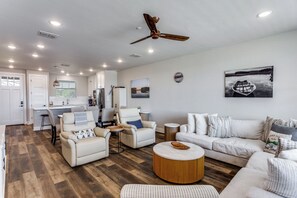 A spacious living area with a ceiling fan, a round wooden coffee table, and a white sofa.