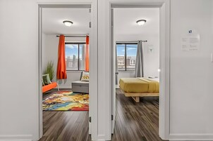 Un apartamento moderno con sofá, cama, alfombra colorida y vistas a la ciudad.