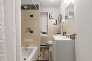 A modern bathroom with a bathtub, toilet, and sink. - West Philly Suites (Philadelphia)
