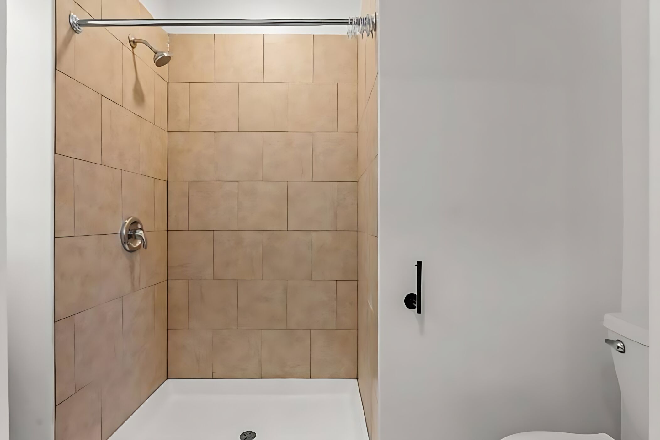 A shower with beige tiles, a white bathtub, and a white toilet.