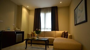 A living room with a sofa, a coffee table, and a small cabinet. - Premium Strato Hotel (Doha)