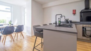 A modern kitchen with a central island, a dining area with chairs, and a view of the outdoors. - Single ensuite room nr Falkirk with self-check-in (Grangemouth)