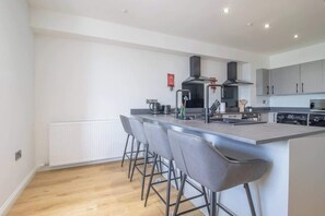 A modern kitchen with a central island, bar stools, and a built-in oven.