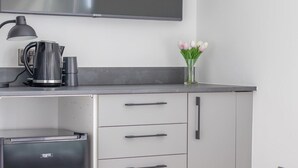 A modern kitchen with a flat-screen TV, a kettle, and a vase with tulips. - Double Ensuite Room + Shared Kitchen + Fast Wi-Fi (Grangemouth)