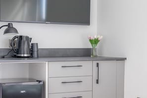 Une cuisine moderne équipée d’un téléviseur à écran plat, d’une bouilloire et d’un vase de tulipes.