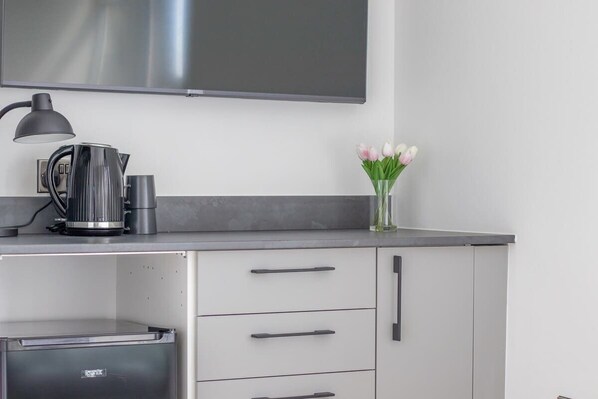 A modern kitchen with a flat-screen TV, a kettle, and a vase with tulips. - Double Ensuite Room + Shared Kitchen + Fast Wi-Fi (Grangemouth)