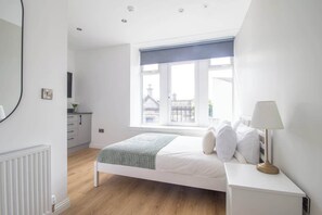 A bedroom with a bed, bedside table, lamp, window, and a view of buildings outside. - Double Ensuite Room + Shared Kitchen + Fast Wi-Fi (Grangemouth)