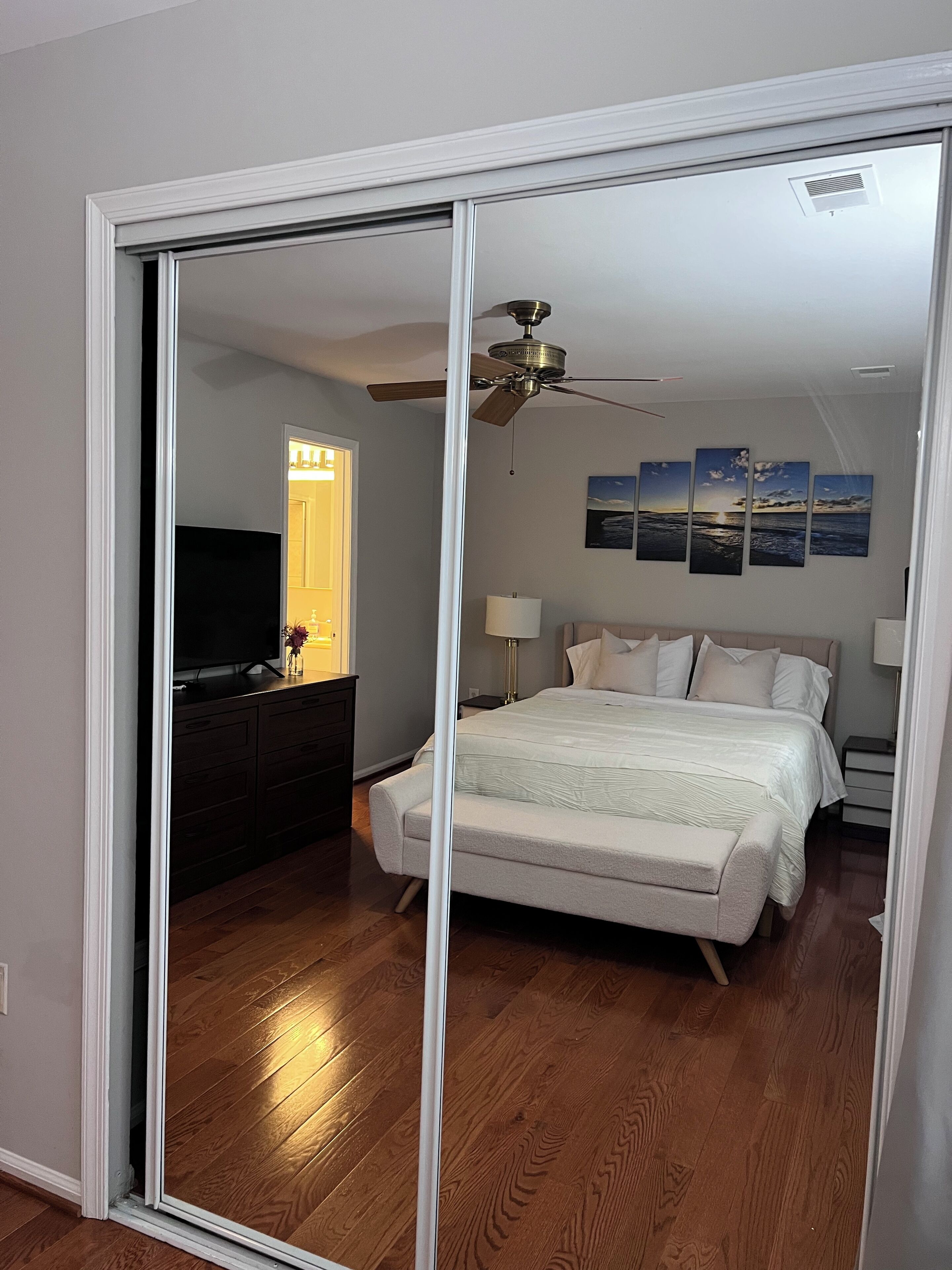 Une chambre à coucher avec un lit, un ventilateur de plafond, une télévision et des œuvres d’art accrochées au mur.
