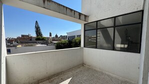 Un balcón con vistas a un paisaje urbano, incluyendo edificios y una torre de iglesia.