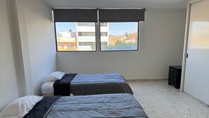 Una habitación con dos camas, una ventana y una puerta.