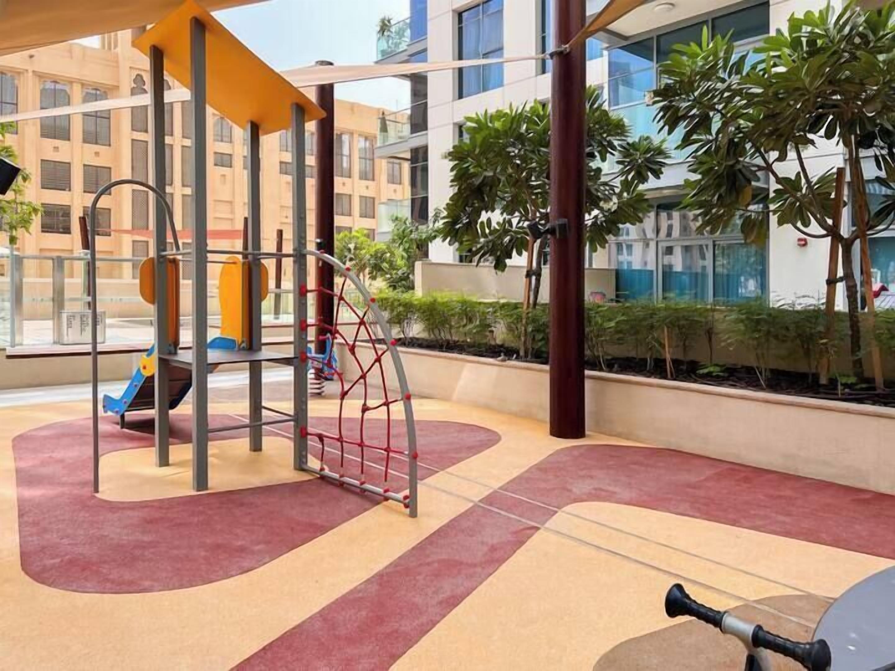 An outdoor play area with a climbing structure, a slide, and a swing set.