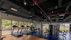 A gym with treadmills, weight machines, and a large window overlooking greenery. - Vogue | Downtown near Dubai Mall | Burj Khalifa (Dubai)