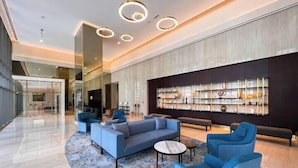A modern lobby with a blue sofa set, a coffee table, and a bookshelf. - Vogue | Downtown near Dubai Mall | Burj Khalifa (Dubai)