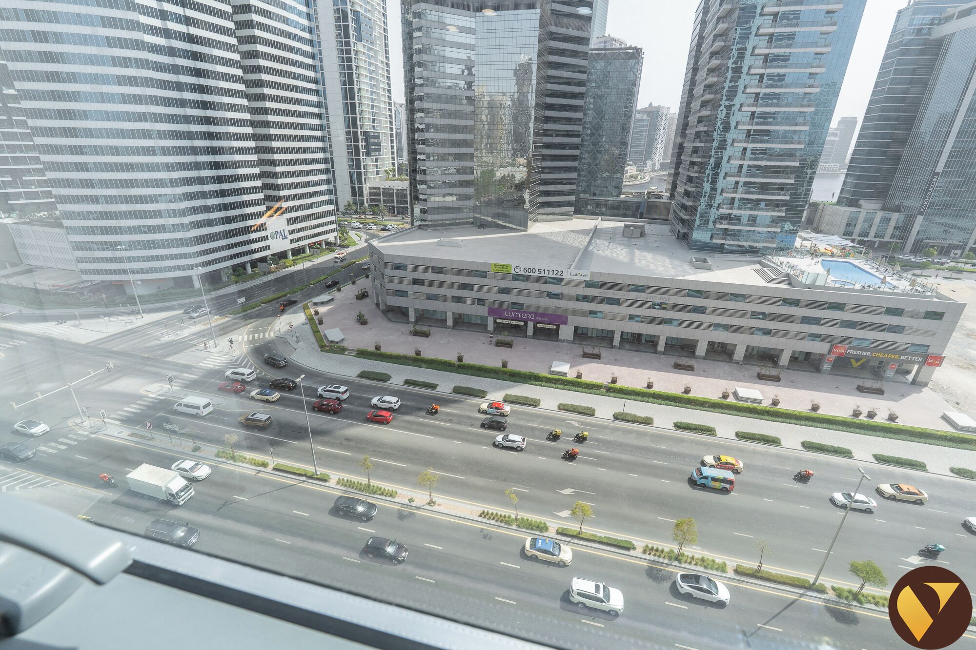 A modern building with a glass facade, surrounded by a busy urban street with cars and motorcycles.