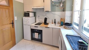 Cocina compacta con microondas, horno y lavabo. Hay una ventana que da al exterior.