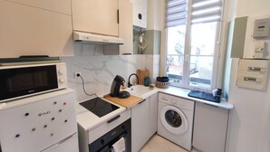 Una cocina compacta con microondas, estufa y lavadora.