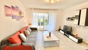 A modern living room with a sofa, coffee table, TV, and cabinets. - Beautiful apartment for 5 with swimming pool (Saint-Raphaël)