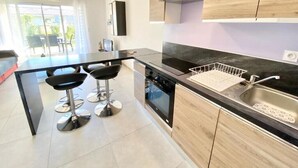 A modern kitchen with a central island, bar stools, and a large window. - Beautiful apartment for 5 with swimming pool (Saint-Raphaël)