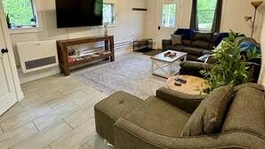 A living room with a sofa, a coffee table, a TV, and a fireplace. - Brand new 2BR, 1.5BA-close to amenities yet feels secluded. 2 story, AC, wifi! (Bridgton)