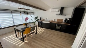 Eine moderne Küche mit Essbereich, mit Holzboden, schwarzen Schränken und einem eingebauten Ofen.
