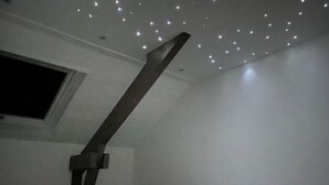 Ein Zimmer mit schrägem Dach, einem Fenster und einem Bett mit weißer Bettwäsche.
