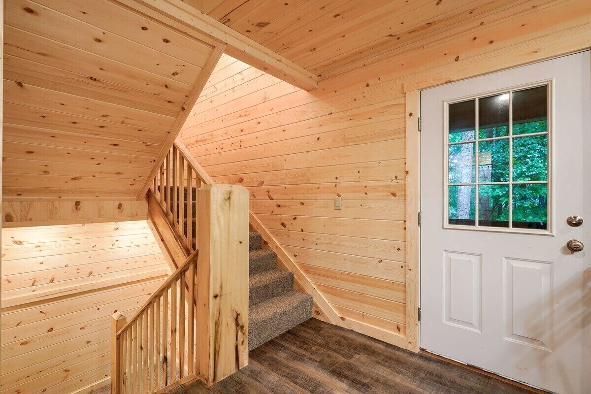 A wooden staircase with a handrail leading to a white door with a window.