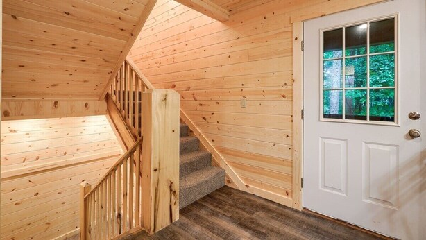 A wooden staircase with a handrail leading to a white door with a window.