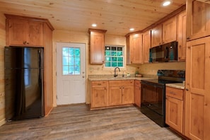 A kitchen with wooden cabinets, a stainless steel refrigerator, a microwave, and a stove.