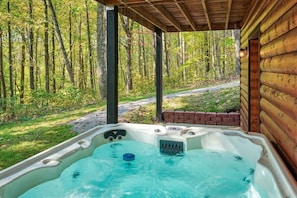 Uma banheira de hidromassagem em uma cabana de madeira com vista para a floresta.
